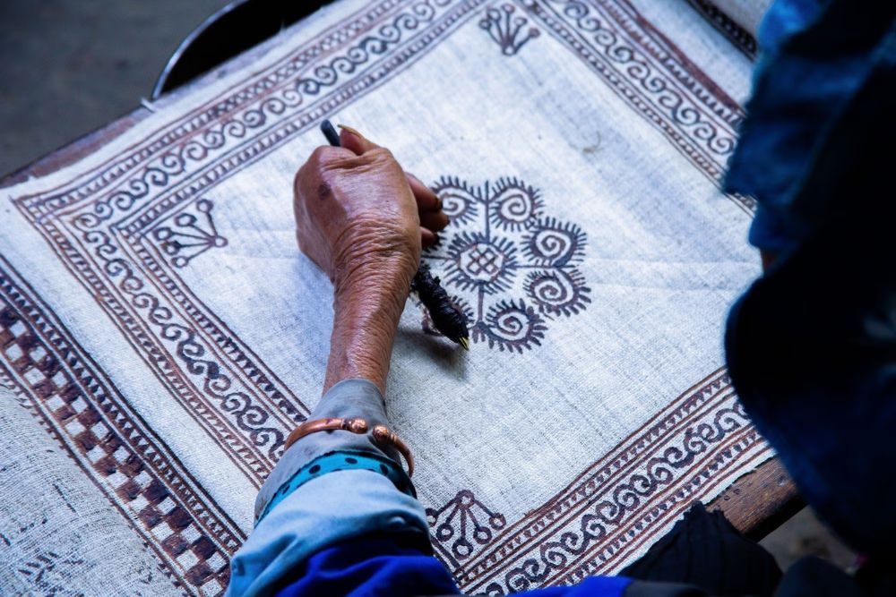 Artisane traçant des motifs à la cire d'abeille sur le lin à Lung Tam