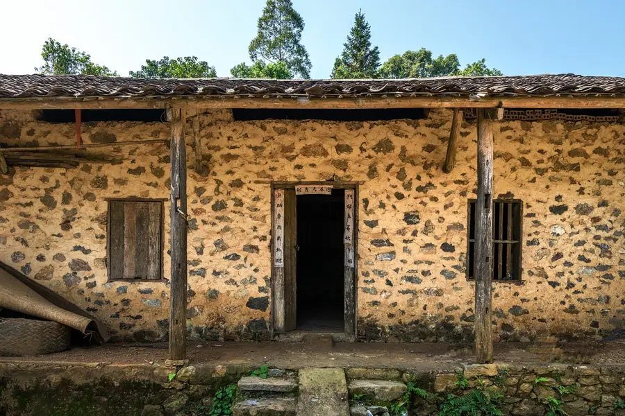 Façade d'une maison de pierre traditionnelle au toit de tuiles yin-yang à Khuoi Ky
