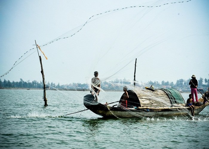 Pêcheur lançant son filet sur la lagune de Tam Giang