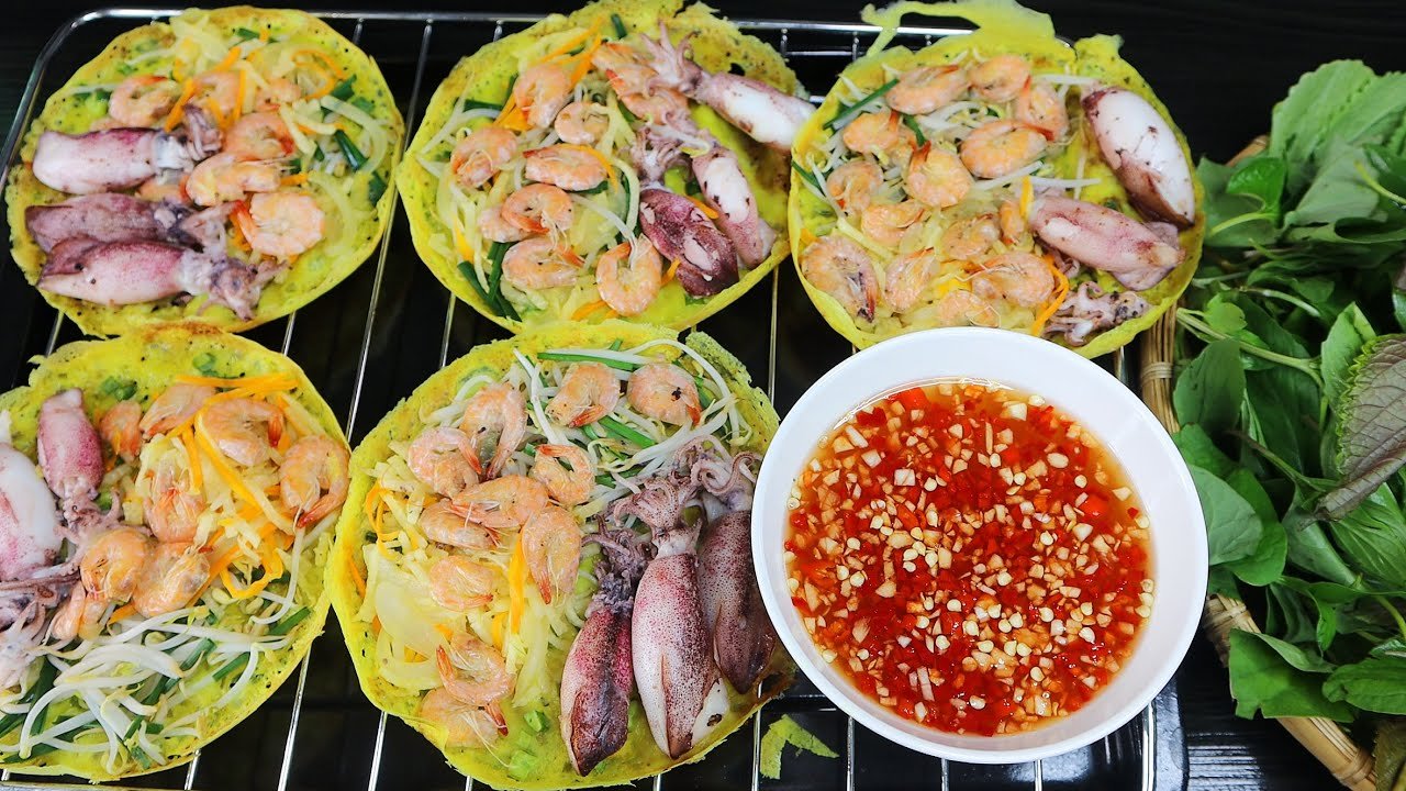 Banh xeo muc, crepes vietnamiennes croustillantes garnies de crevettes et de calamars, servies avec herbes fraiches