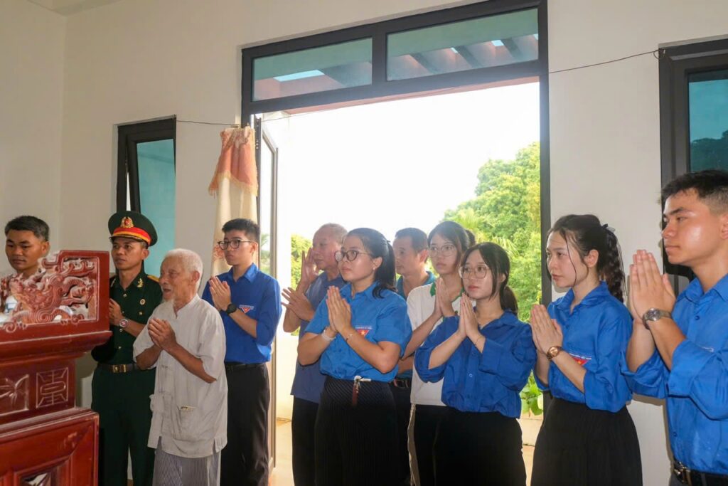 Volontaires en prière aux côtés d'une famille de martyr, commune de Ứng Thiên