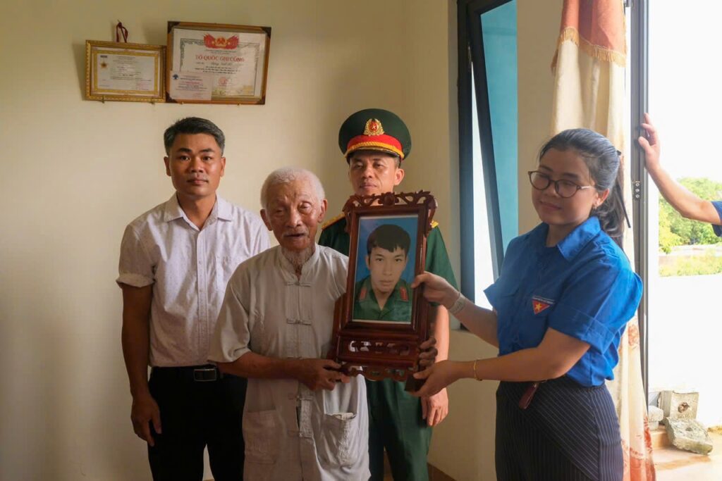 Remise d'un portrait encadré à la famille d'un martyr de la patrie, en présence d'un officier militaire
