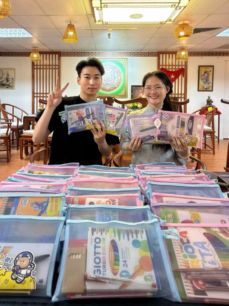 Deux membres de l'équipe Horizon Vietnam Travel préparant les trousses scolaires offertes aux enfants de la campagne Hạ Chí 2026