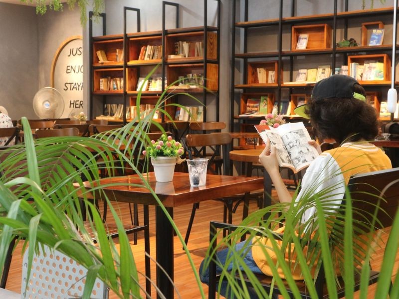 Jeune femme lisant dans un café cosy près de la rue du livre Nguyen Van Binh