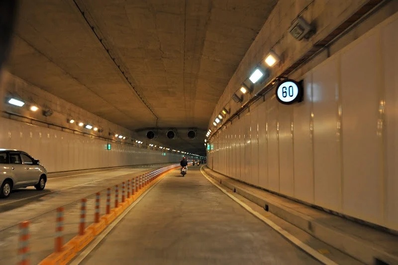 Chaussée éclairée à l'intérieur du passage souterrain, empruntée par voitures et deux-roues