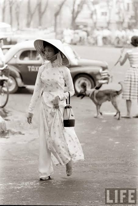 Femme vietnamienne en ao dai blanc dans une rue de Saigon, photographie d'époque