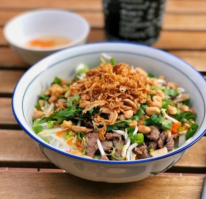 Bol de bun bo Nam Bo avec bœuf, carottes et herbes aromatiques dans une gargote vietnamienne