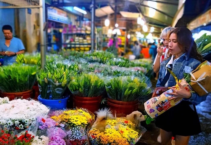 Acheteurs et vendeurs de fleurs dans l'agitation nocturne du marché de Ho Thi Ky