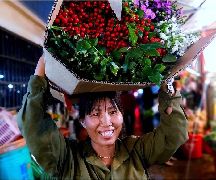 Marchande transportant des bottes de fleurs fraîches au marché de Ho Thi Ky