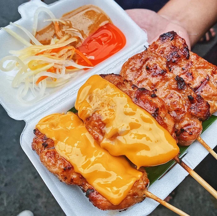 Brochettes de porc grillées nappées de fromage fondu, spécialité de rue du marché de Ho Thi Ky