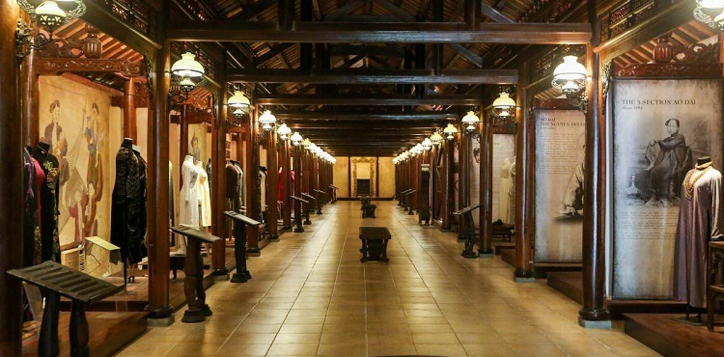 Long couloir en bois sculpté du musée de l'Ao Dai, bordé de mannequins en costume traditionnel