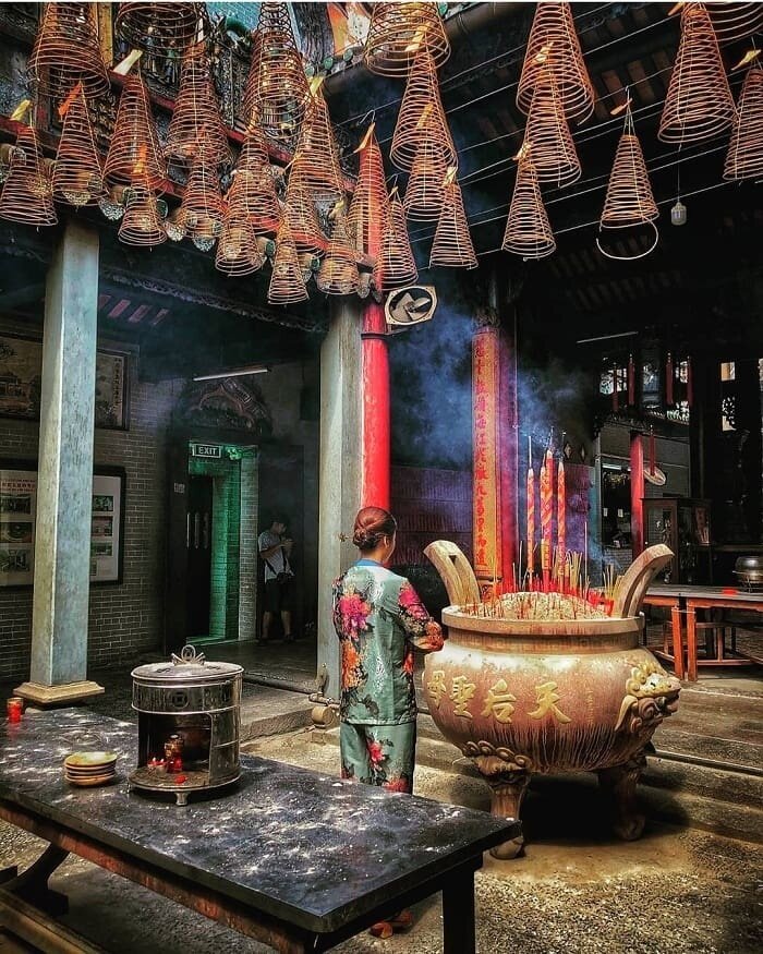 Fidèle en prière devant un grand brûleur d'encens à la Pagode de l'Empereur de Jade