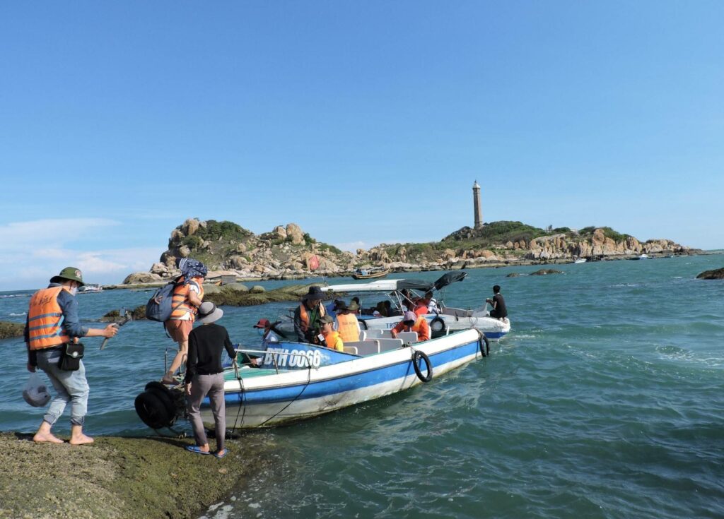Touristes embarquant en bateau pour rejoindre l'île du phare de Ke Ga