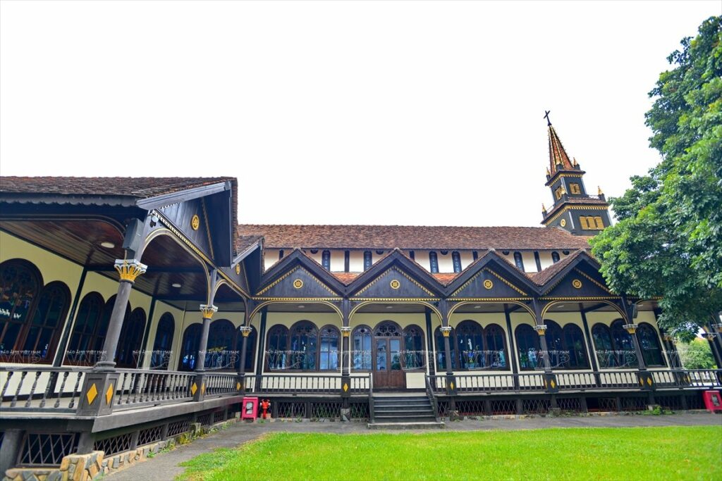Vue extérieure de l'église en bois de Kon Tum entourée de verdure