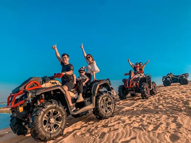 Une famille souriante lors d'une excursion en quad sur les dunes blanches de Bau Trang