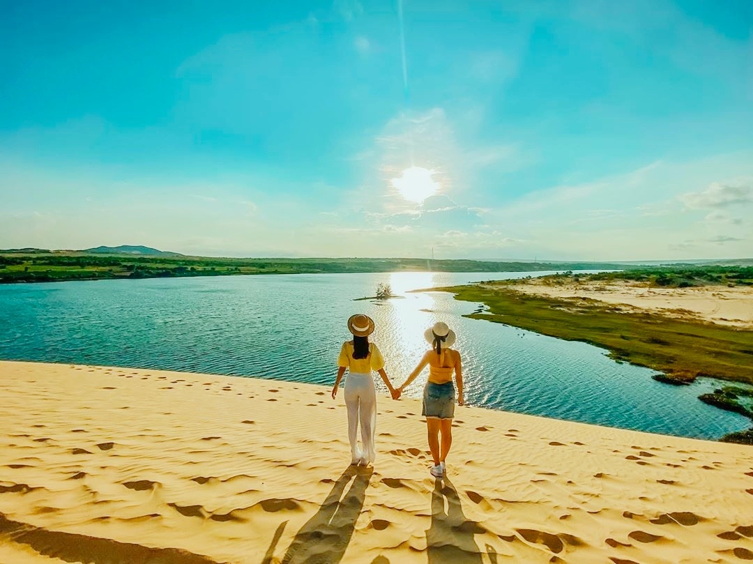 Un couple admirant le lac de Bau Trang depuis le sommet d'une dune blanche