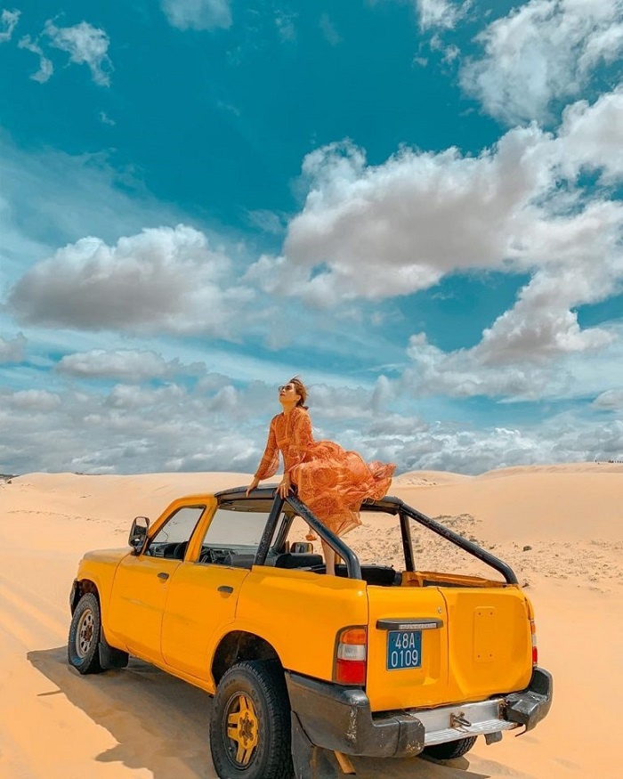 Deux visiteurs dévalant les dunes blanches de Bau Trang en glisse sur planche de sable