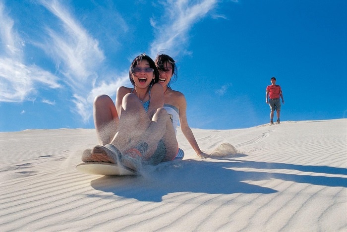 Un couple prenant la pose sur un chameau au sommet des dunes blanches de Bau Trang