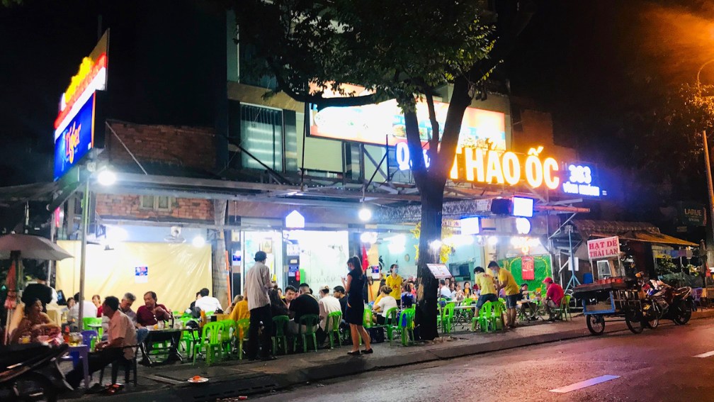 Restaurant de rue animé le soir avec des tables basses colorées