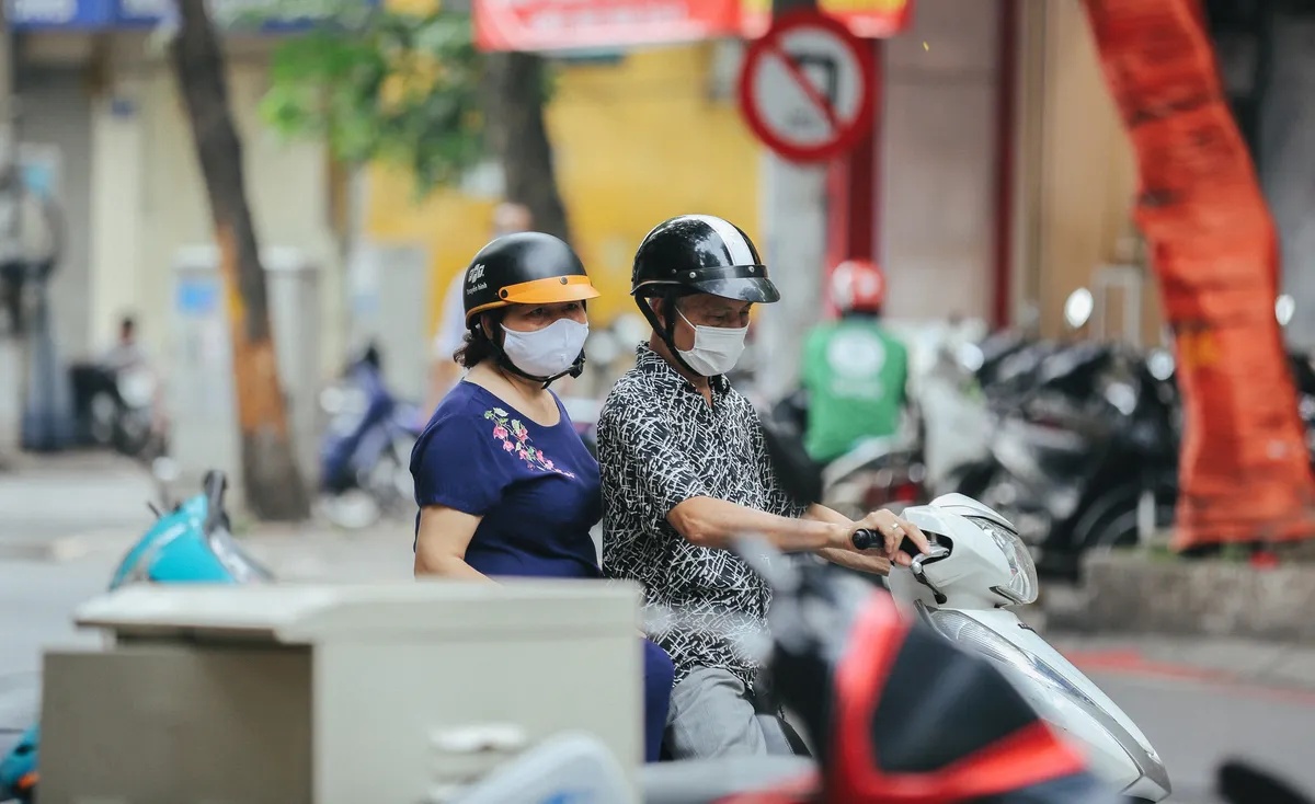 A couple wearing protective masks on a motorbike in a Vietnamese street