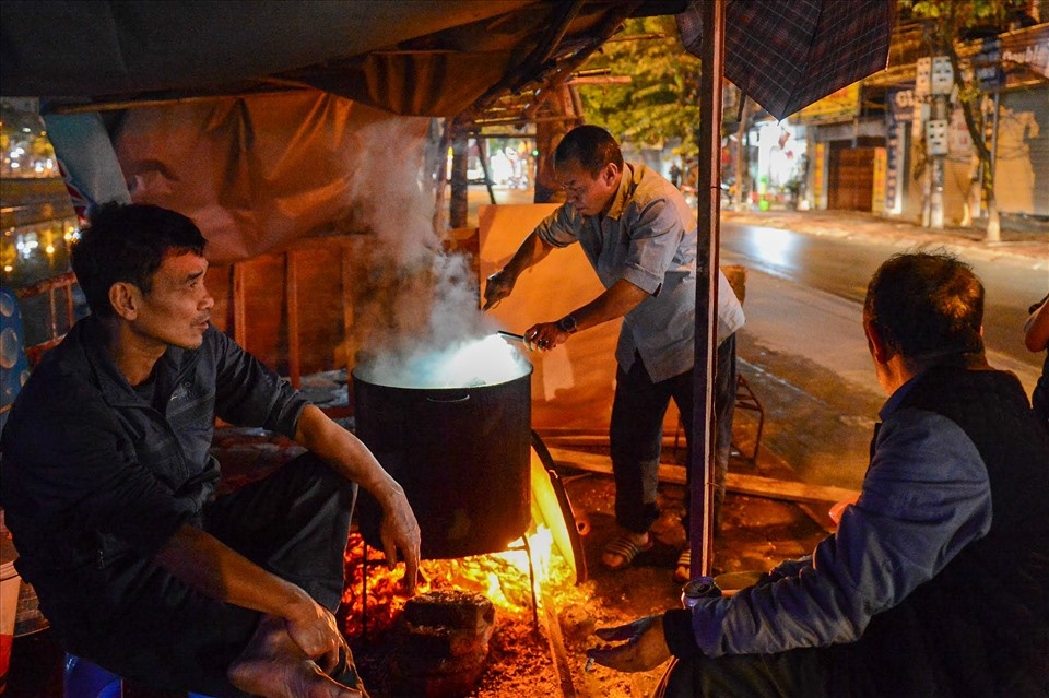 Cuisson des banh chung dans un grand chaudron au feu de bois pendant plusieurs heures