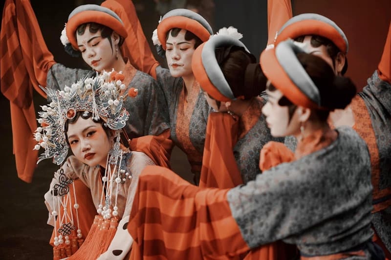 Künstler der Hoa-Ethnie in traditioneller orangefarbener Tracht bei einer Aufführung in Ho-Chi-Minh-Stadt