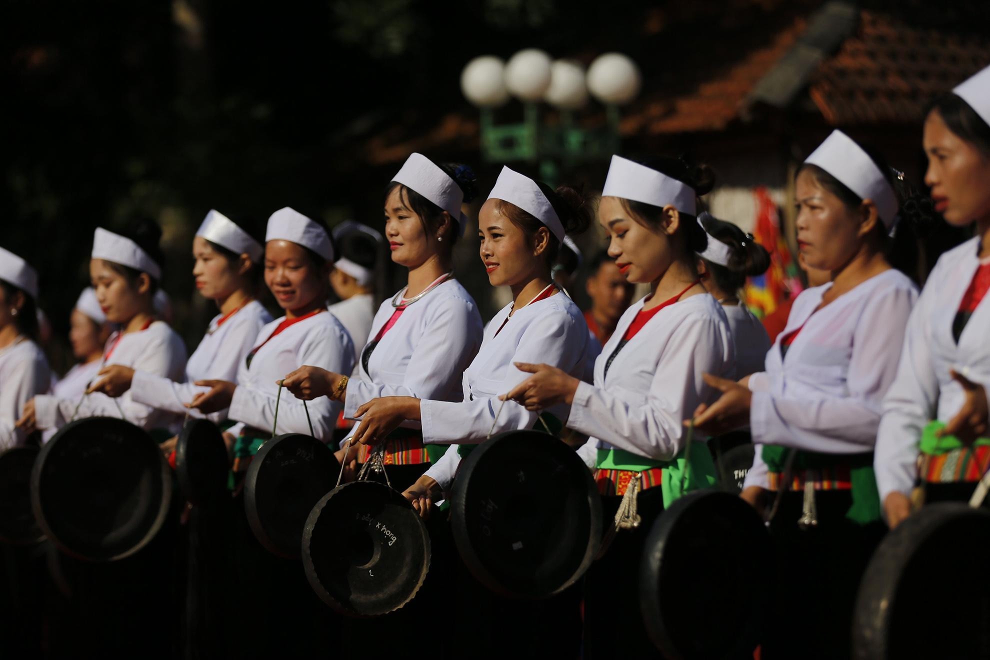 Muong-Frauen in traditioneller weißer Tracht beim Gongspiel während eines Festes