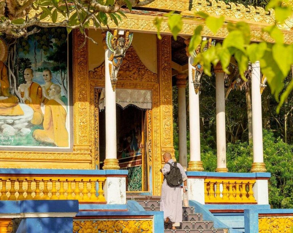 Un moine gravit les marches menant à l'entrée d'un bâtiment de la pagode