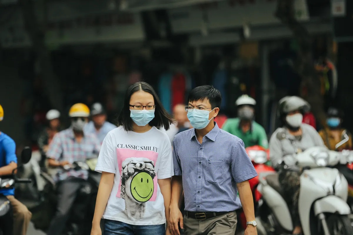 Two people wearing surgical masks in a busy street