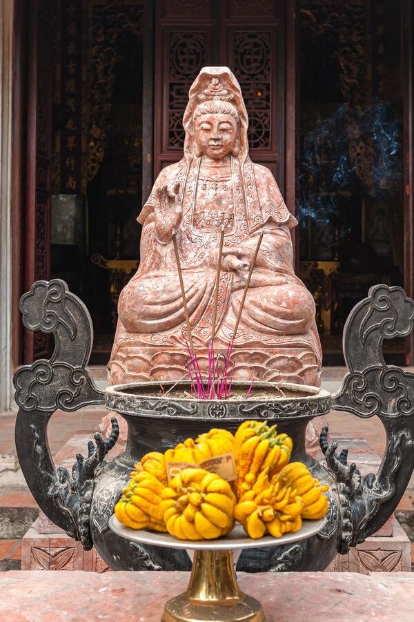 Statue de Quan Âm entourée d'encens dans une pagode vietnamienne