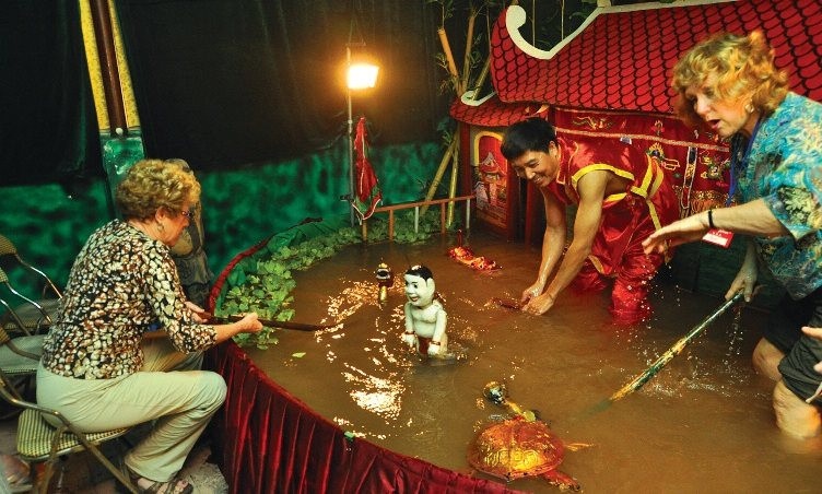 Touristes découvrant les marionnettes sur l'eau dans un village artisanal au Vietnam