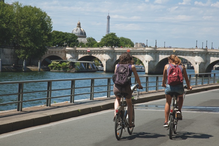 Deux cyclistes longeant la Seine à Paris avec la tour Eiffel en arrière-plan