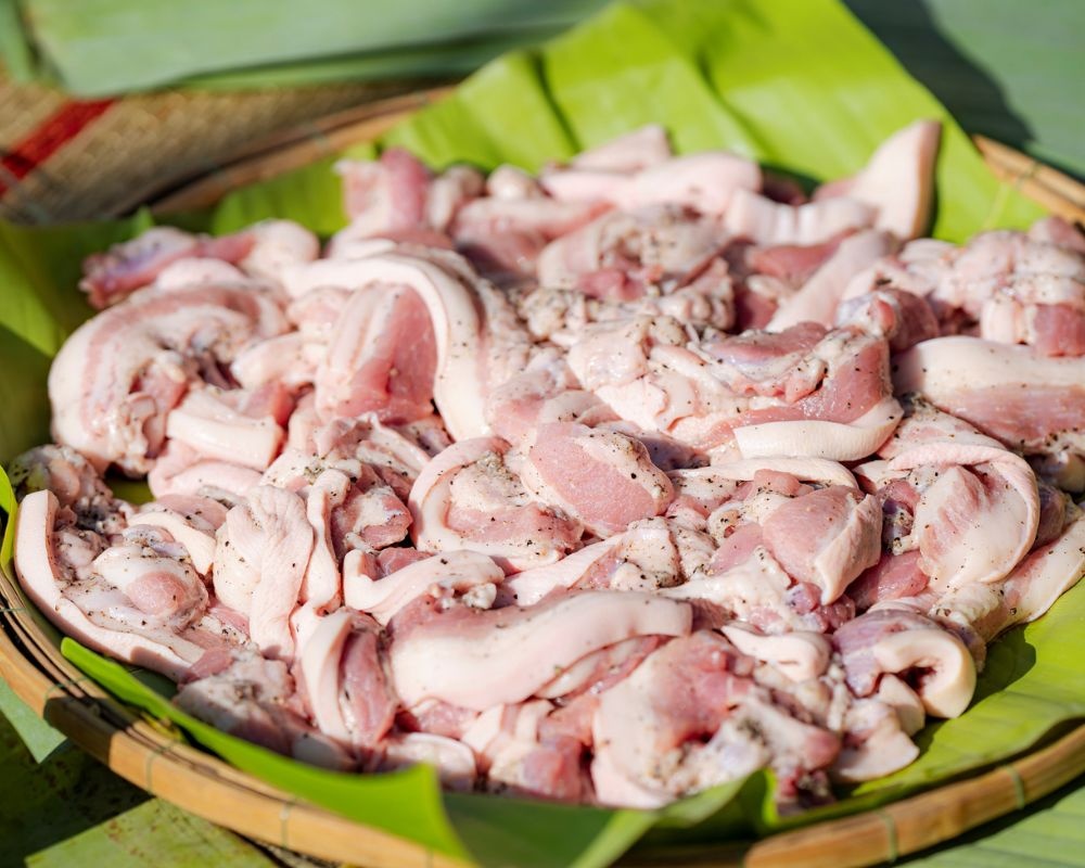Poitrine de porc découpée et assaisonnée avant d'être placée au cœur du banh chung