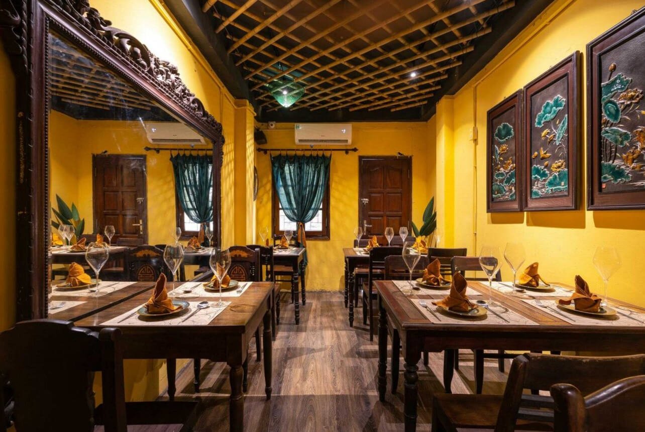 Intérieur chaleureux du restaurant Cai Mam Bistro avec murs jaunes et décoration traditionnelle