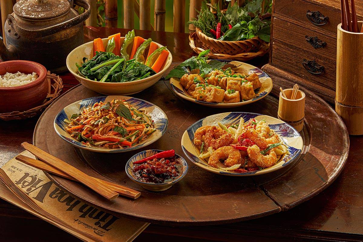 Un mâm cơm traditionnel au Cai Mam Bistro avec crevettes frites, légumes sautés et tofu