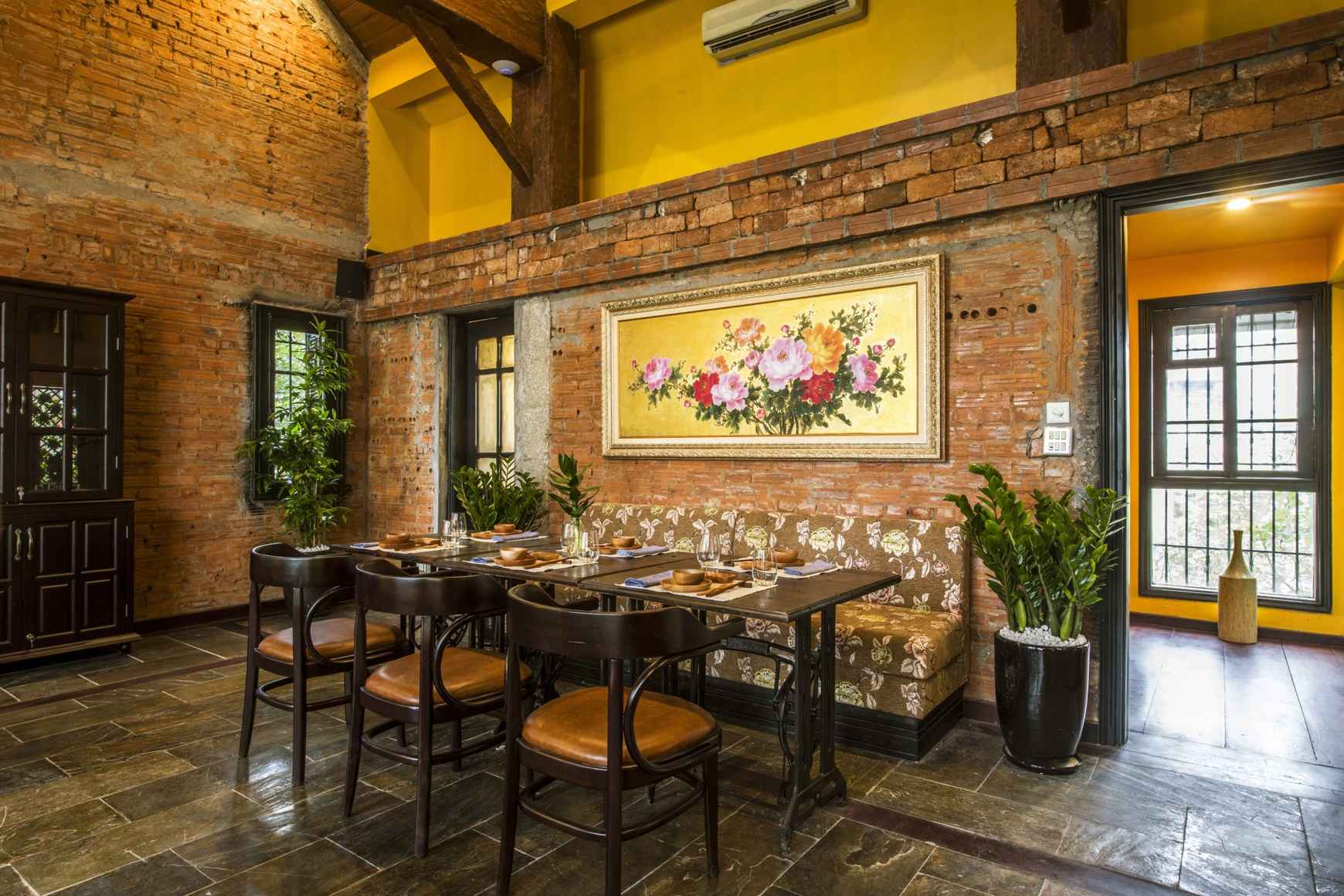 Interieur du restaurant HOME Hanoi avec arches et mobilier colonial en bois sombre
