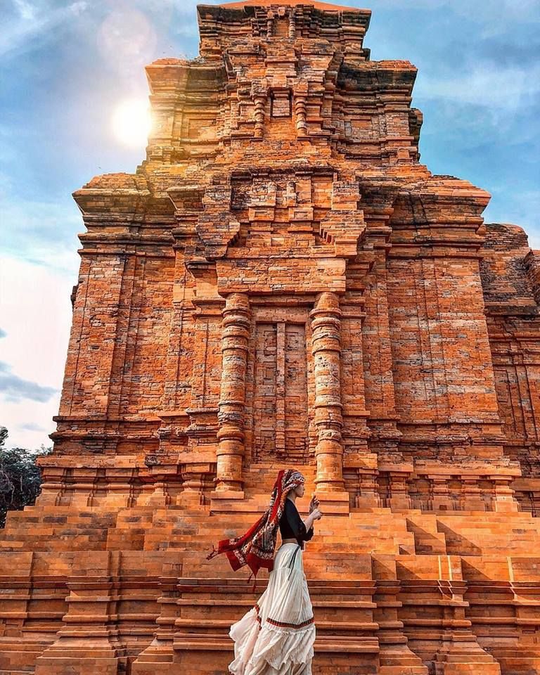 Femme en costume traditionnel cham devant la tour de Po Sah Inu au coucher du soleil
