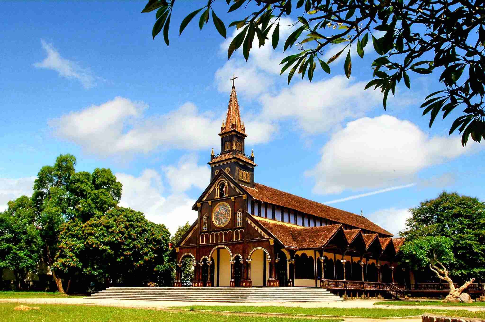 Église en bois de Kon Tum avec son clocher pointu surmonté d’une croix et ses arches en bois sculpté