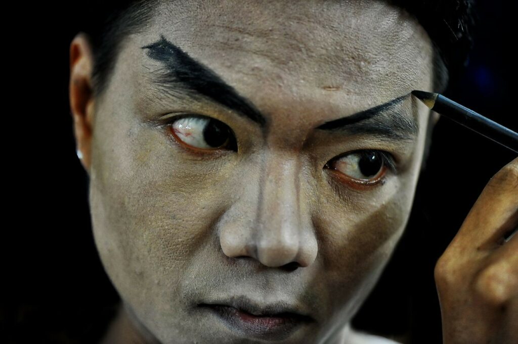 Acteur de Tuồng se maquillant les sourcils en coulisses