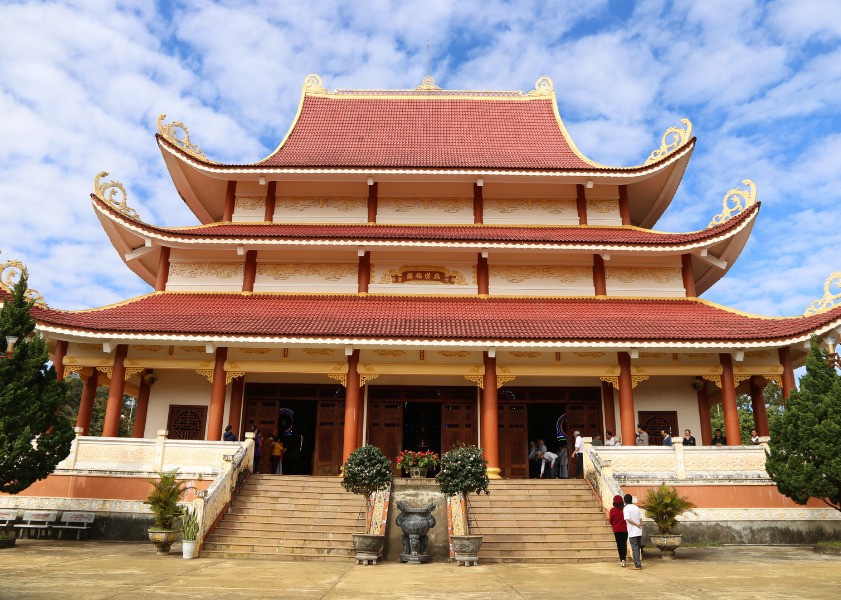 Façade rouge et or de la pagode Khanh Lam avec visiteurs montant les marches