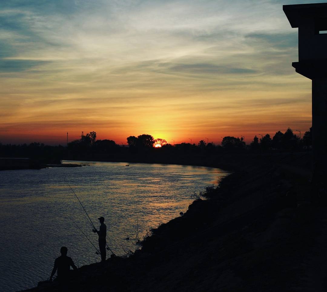 Silhouette d’un pêcheur solitaire au coucher du soleil sur les berges de la Đăk Bla à Kon Tum