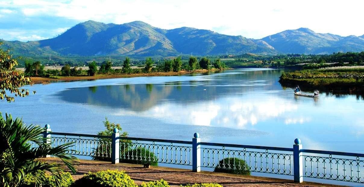 Panorama sur la Đăk Bla depuis la promenade de Kon Tum avec balustrade bleue et blanche et pirogue au loin