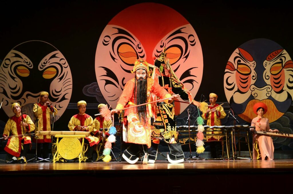 Artiste de Tuồng avec maquillage traditionnel devant des masques de théâtre vietnamien