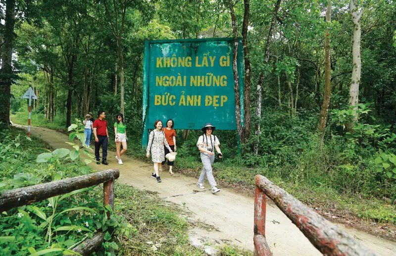 Visiteurs pratiquant l'écotourisme à Chu Mom Ray devant un panneau de sensibilisation environnementale