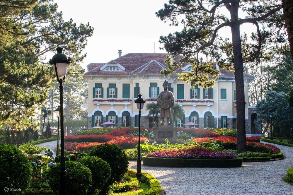 Jardin fleuri et statue devant une résidence historique à Dalat.