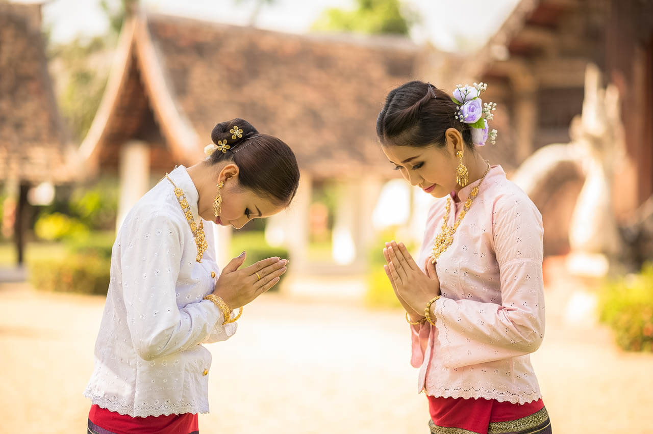Deux femmes effectuant la salutation traditionnelle wai en Thaïlande