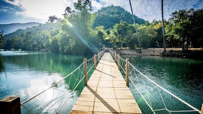 Passerelle en bois au-dessus de l’eau dans la zone écotouristique de Ba Ho