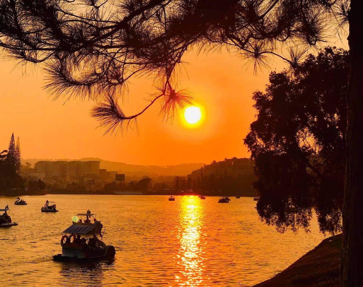 Coucher de soleil sur le lac Xuan Huong avec barques et reflets.