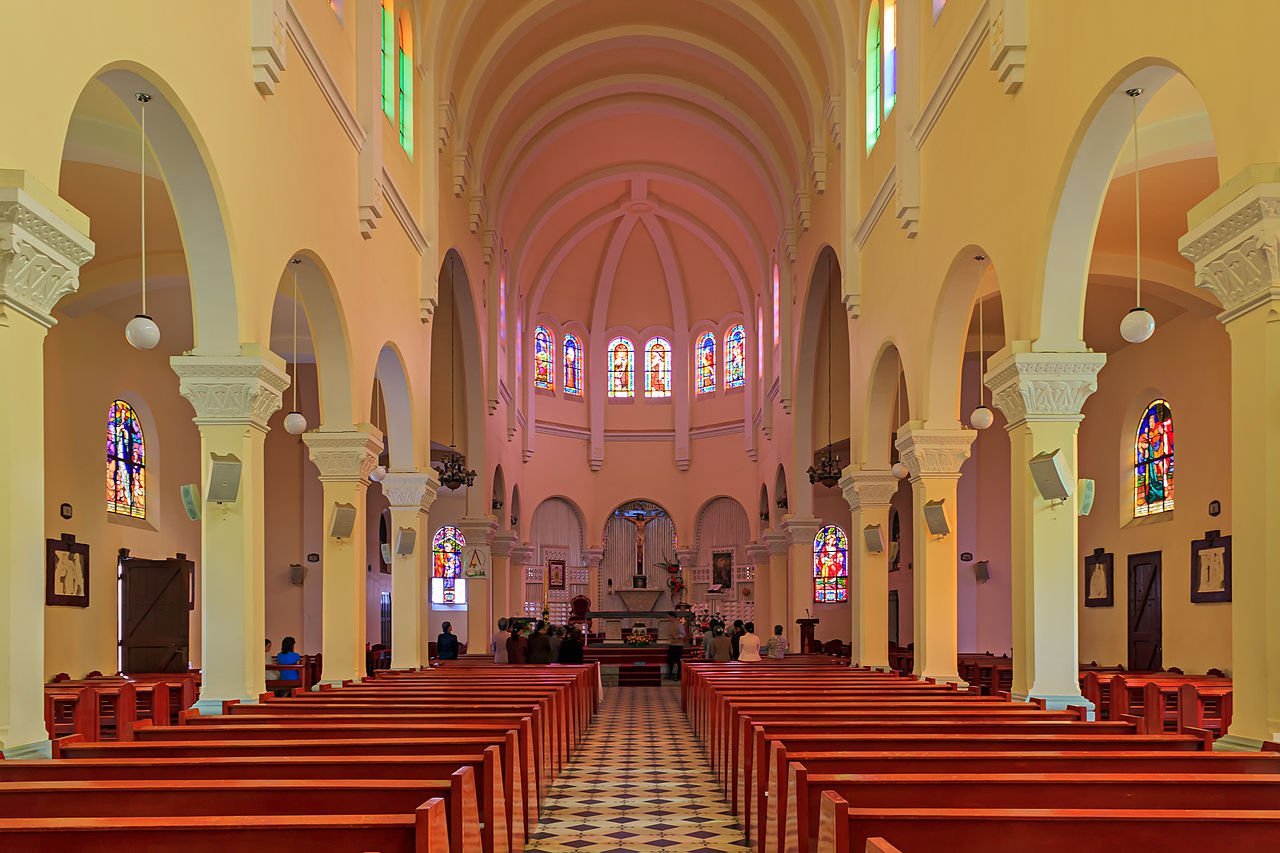 Nef intérieure de la cathédrale avec arches et vitraux colorés.
