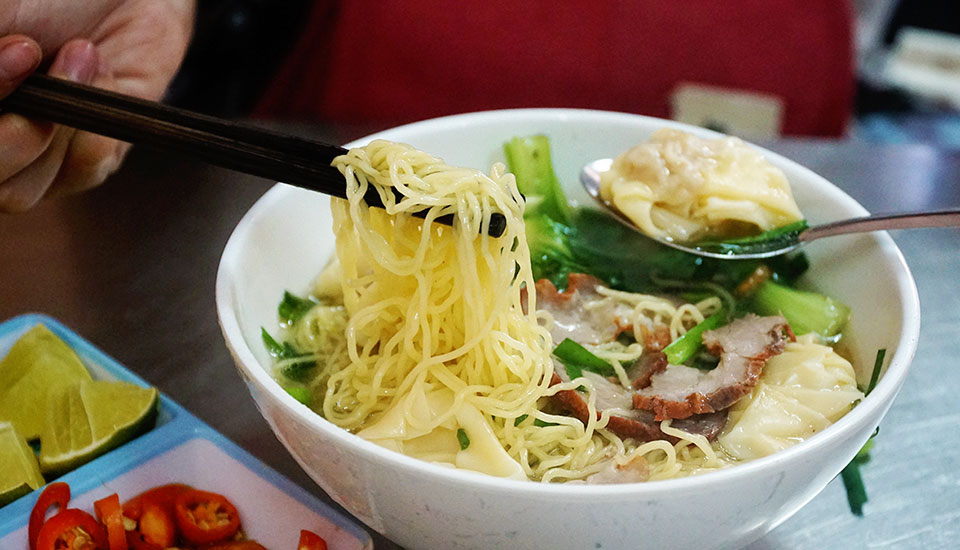 Des nouilles chinoises artisanales servies en soupe avec des raviolis et du porc rôti.